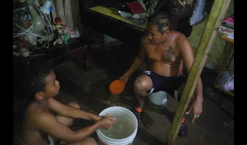 Ovidio, con la ayuda de su hijo, saca toda el agua que se metió a su vivienda. Foto: Jesús Simmons