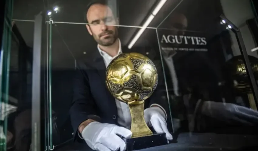 Francois Thierry, experto en deportes de la casa de subastas Aguttes, instala en la caja el trofeo del Balón de Oro de Diego Maradona. EFE/EPA/Christophe Petit Tesson